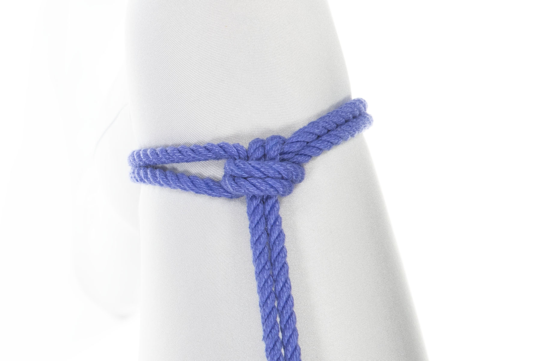 A blue rope has been tied around a thigh in a single column tie with a single wrap. The rope is pulled up the thigh, toward the body.