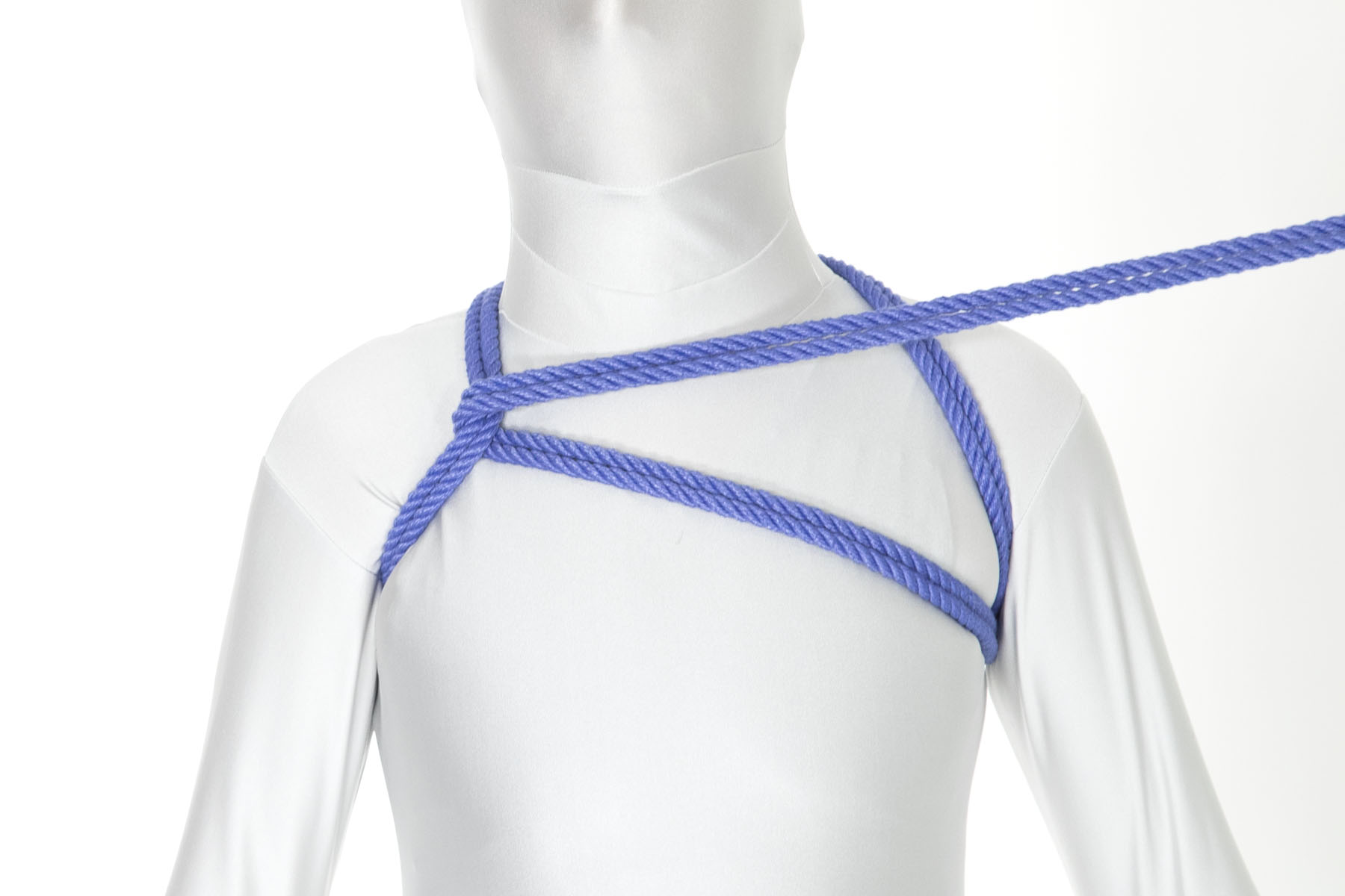 The rope goes under the right shoulder line and doubles back across it, travelling horizontally across the chest toward the left shoulder.