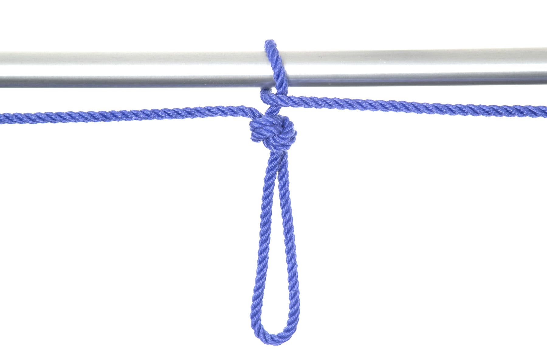 The rope exiting the overhand knot goes over and around the pipe, coming around itself on the left and then exiting the frame to the right. The crossover secures the loop to the pipe.