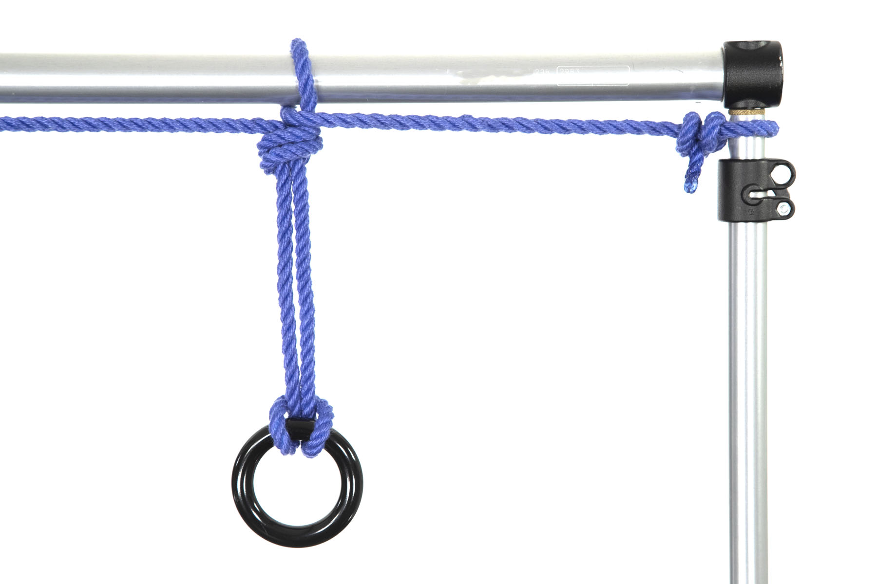 A one inch aluminum pipe enters the frame from the left. Near the right edge of the frame, it connects at ninety degrees to another pipe that exits the frame to the bottom. A blue rope enters the frame from the left, running along the pipe. It is tied in a on overhand loop knot that is secured to the pipe, and is then tied off to the vertical pipe on the right with two half hitches. A black rappel ring has been attached to the overhand loop using a lark’s head on a bight.