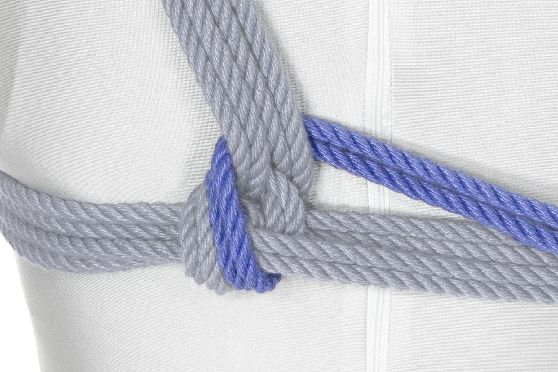 The rope comes over the chest wraps just to the left of the shoulder lines and crosses under the shoulder lines, travelling to the right. The tension on the rope locks the shoulder lines to the chest wraps.