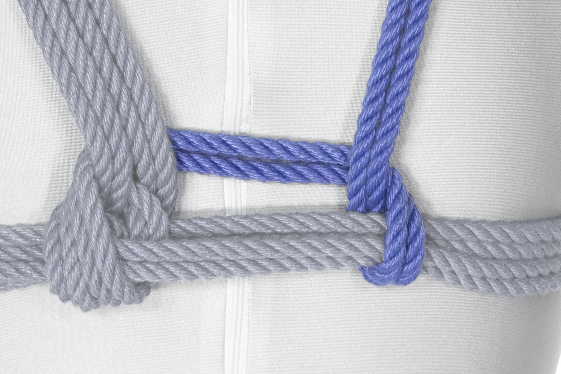 The rope goes three inches to the right of the spine, then makes a 90 degree turn over the chest wraps. It doubles back under the chest wraps and crosses over itself. The left and right of the harness are now symmetrical, with matching crossing structures a few inches on either side of the spine.