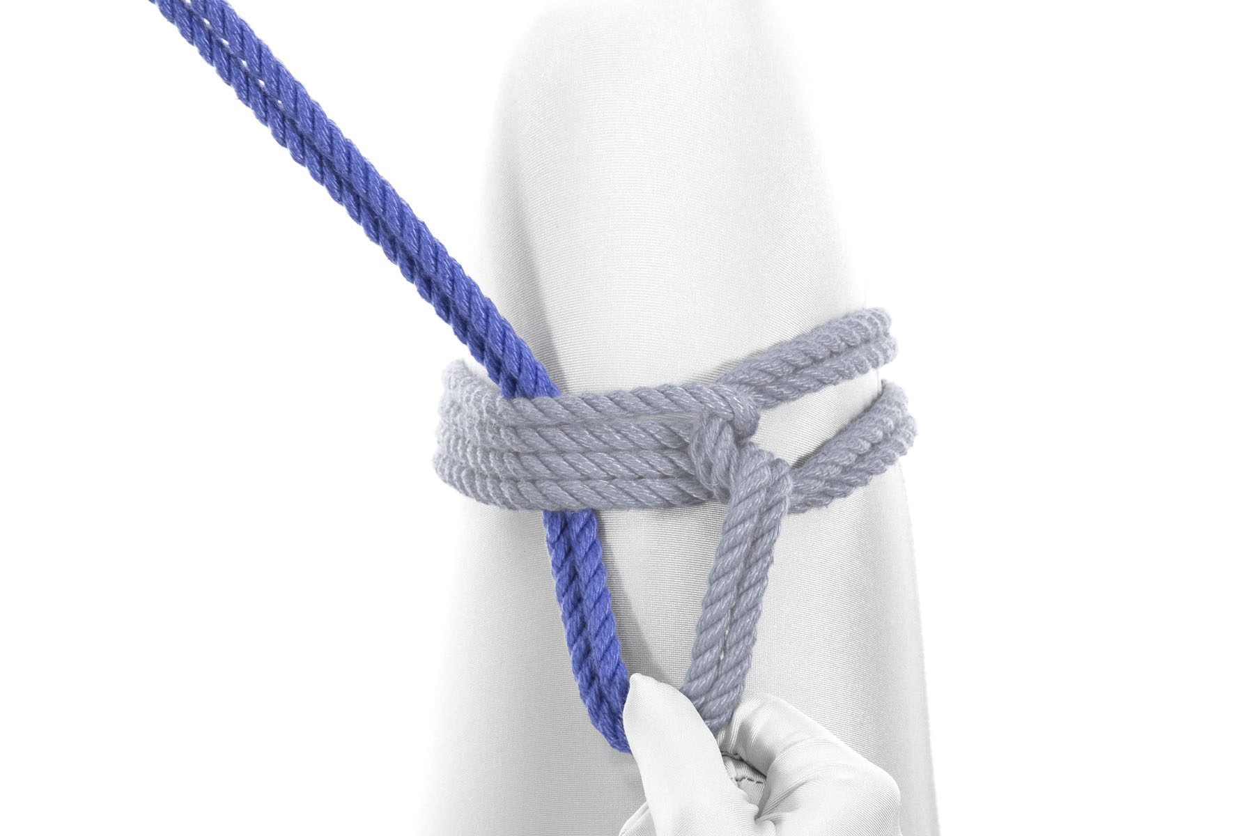 Continuing to pinch the rope with their right hand, the rigger has passed the working end under all four wraps. The rope continues to make a triangle pointing toward the body.
