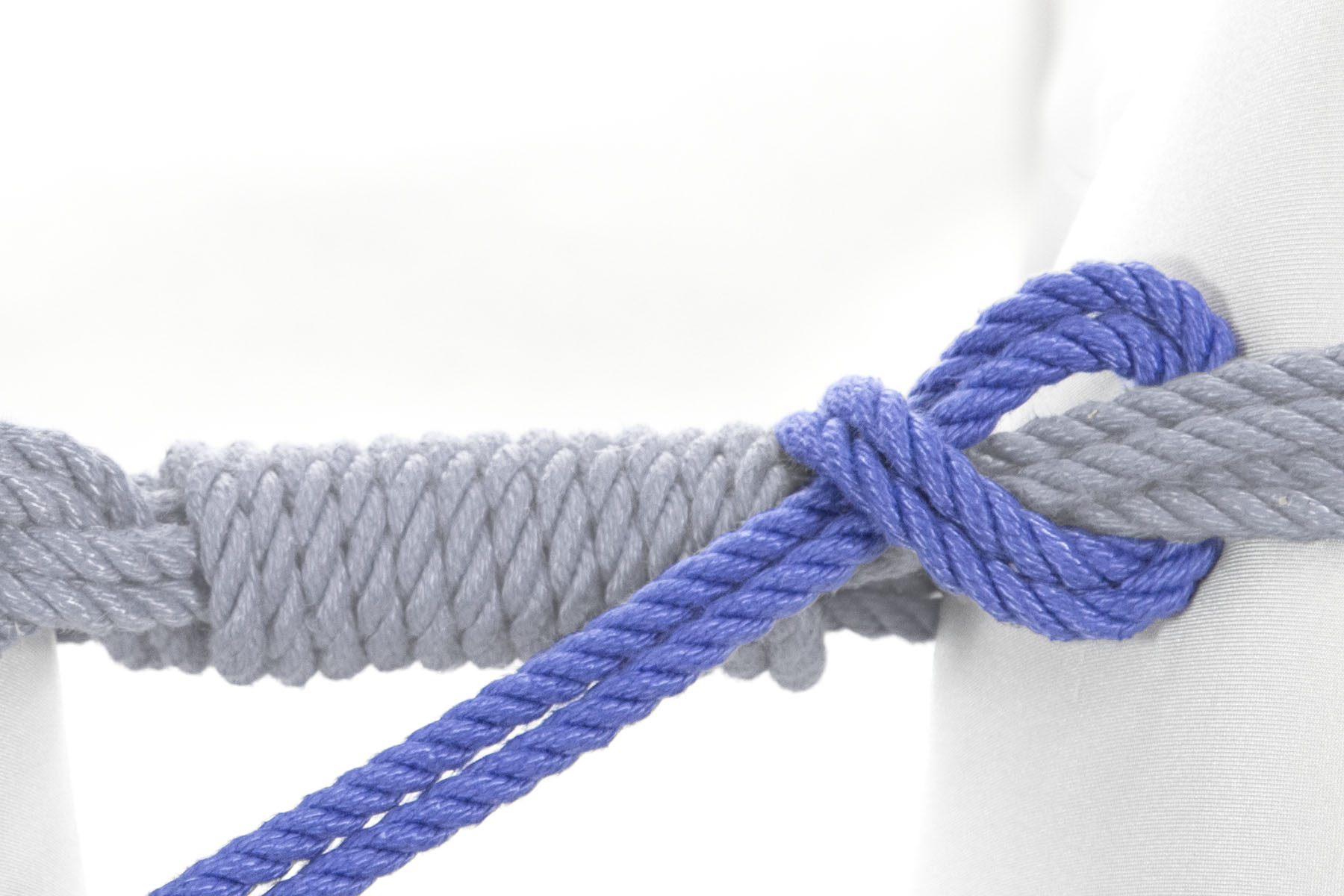The rope doubles back and crosses under itself, making a half hitch around the upper wraps.
