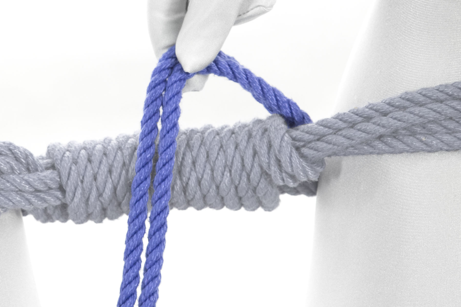 The rigger’s right hand has pulled the rope to the center of the bar tie.