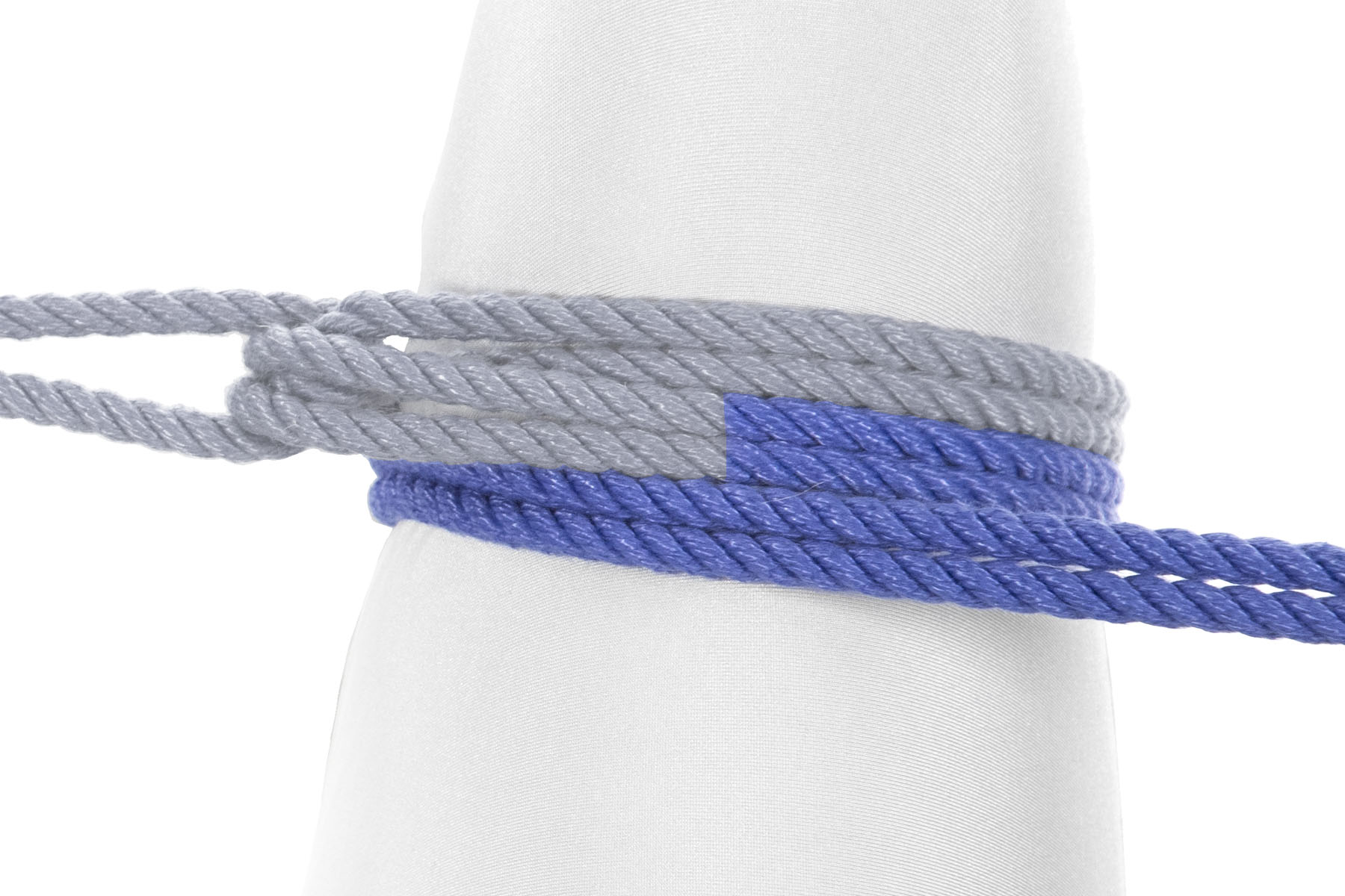 The rope makes a second wrap around the leg, lying against the first wrap on the side closer to the person’s body. This wrap does not go between the two halves of the rope.