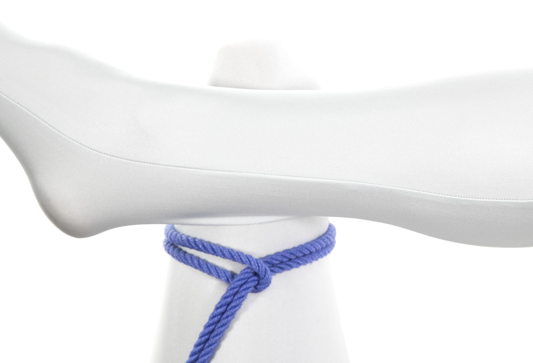 We are looking down at the legs of a seated person in a white bodysuit. The right leg is bent and laid on top of the left leg, with the ankle of the right leg just above the knee of the left leg. The bight of a blue rope goes clockwise around the thigh of the left leg, right above where the ankle crosses it. The rope goes through the bight and is resting on top of the left leg.