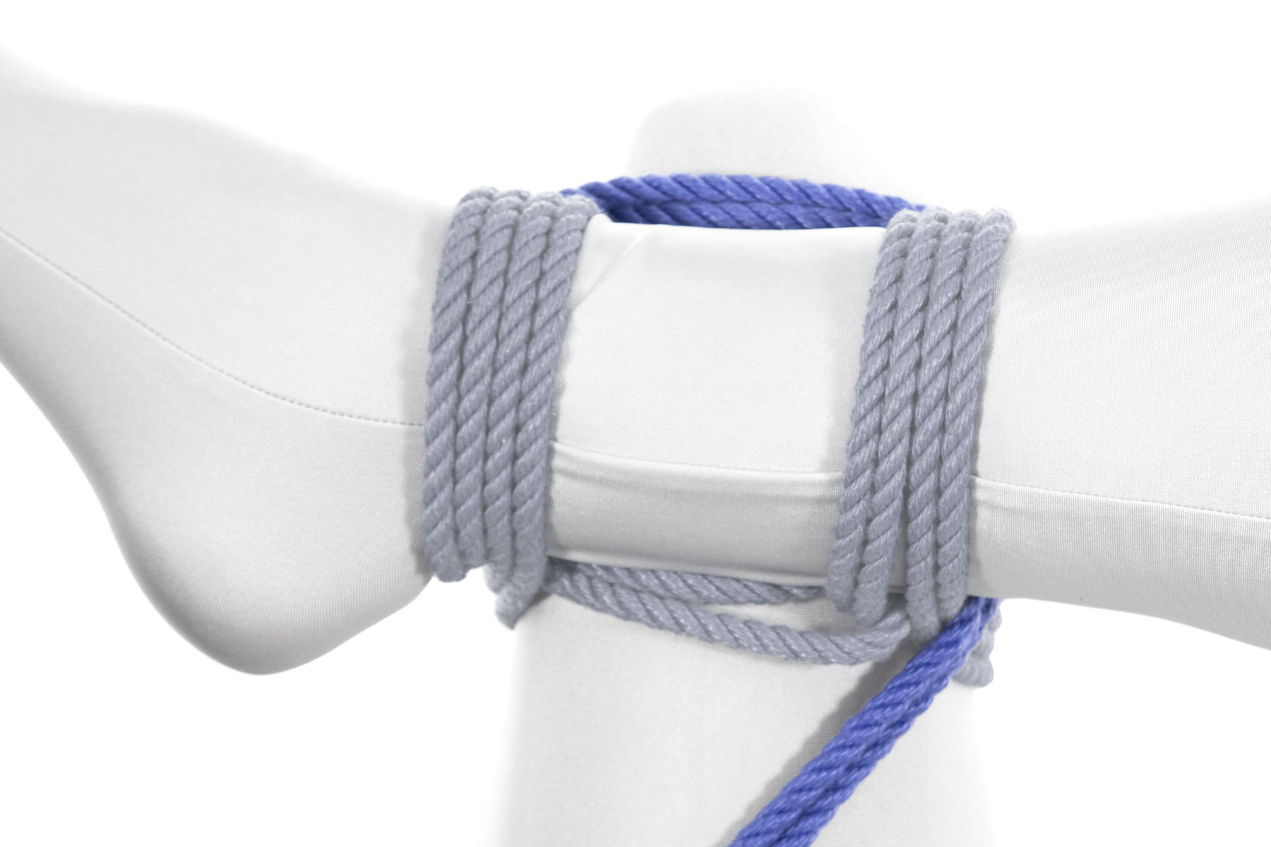 The rope now starts making a square. It crosses to the right over the left leg right above the knee, and wedged against the wraps that bind the right leg to it. It then crosses under the right leg, moving toward the body. It re-emerges on the lower right of the frame.