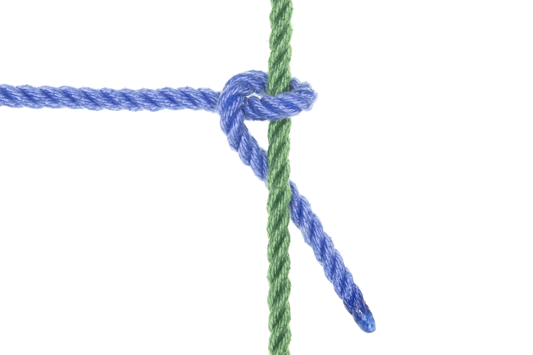 A green rope crosses the frame vertically. A blue rope enters from the left and makes a Munter at the green rope before exiting downward at 45 degrees. This blue rope crosses over the green rope, comes back under the green rope but higher in the frame, then crosses over itself moving downward before going under the green rope again. The 45 degree exit means that the blue rope is being pulled out of the Munter, loosening it.