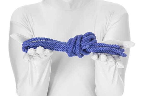 A person holding up a blue rope that has been folded in half three times and tied in a simple overhand knot.