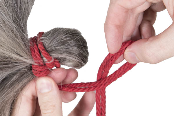 The rigger is repeating the technique to tie a second half hitch around the base of the tie.