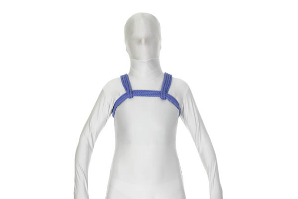 A person in a white bodysuit is wearing a chest harness tied in blue rope. Four strands of rope come under the left armpit, cross high on the chest, and go under the right armpit. A doubled rope comes over each shoulder, goes under and around the chest wrap, and goes back over the same shoulder.