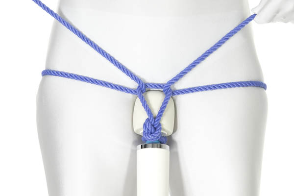 A person in a white bodysuit has a Magic Wand style vibrator hanging directly underneath the crotch, with the head of the vibrator pressed against the crotch. An overhand loop of rope is wedged against the shaft of the vibrator. The rope ends have been split and come around the hips from opposite sides, making reverse tensions on the loop.