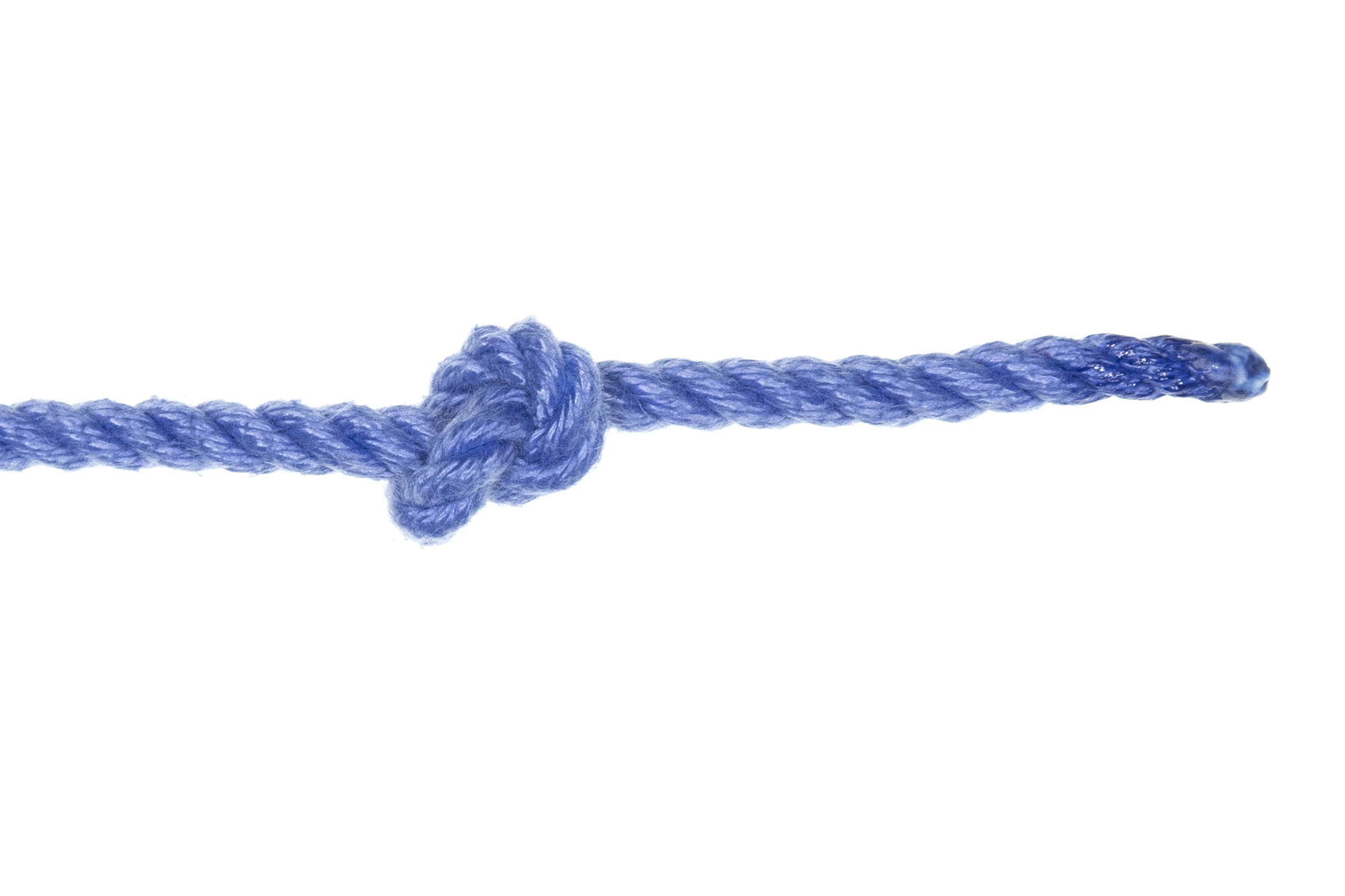 An overhand knot tied in a single length of blue rope. The knot is small and compact, with three inches of working end coming out of it.