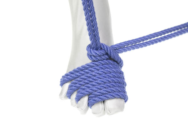 A closeup of a right foot wearing a white bodysuit. A doubled blue rope enters from the top of the image and disappears under four wraps of rope that make a counter-clockwise spiral around the toes. Each wrap goes over the toes before going down between two toes. The wraps are tidy and snug against each other. The tail of the rope is tied in a half hitch around the vertical line and exits to the right of the image.